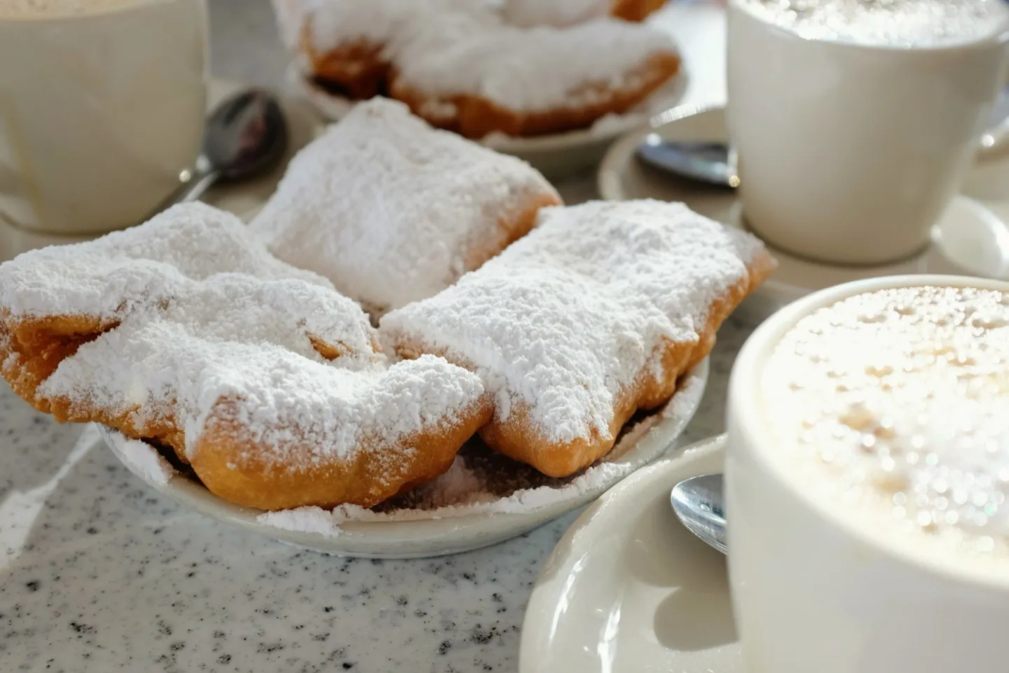 Powdered-sugar beignets and cups of café au lait at Café du Monde in New Orleans.